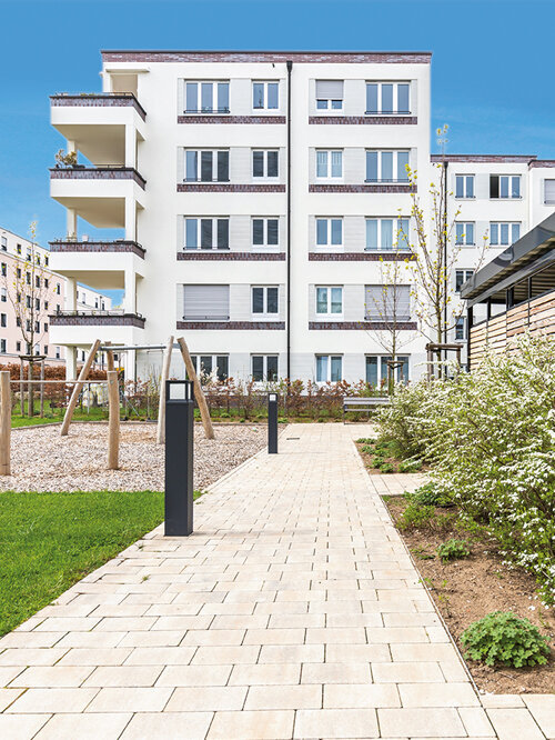 Wohngebäude der Nordstadtgärten in Nürnberg mit heller Fassade, Balkonen, Gehweg und Spielbereich im Innenhof